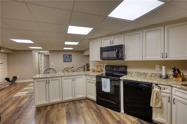 kitchen featuring white cabinetry, a peninsula, black appliances, and dark wood-style floors