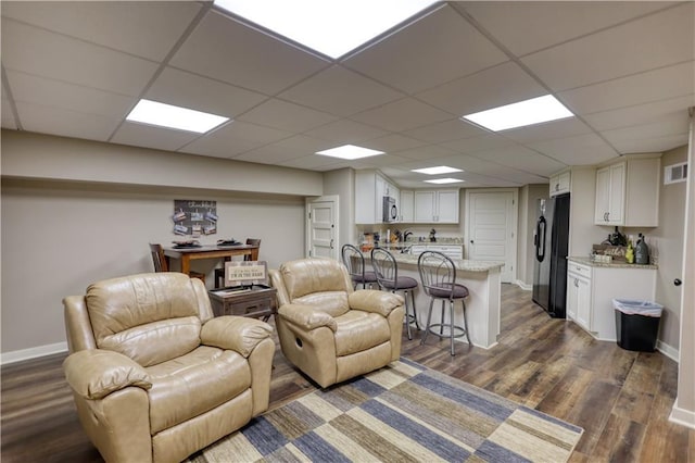 living area with baseboards, dark wood finished floors, and a paneled ceiling