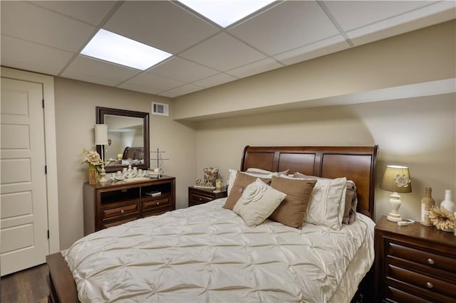 bedroom featuring a drop ceiling, wood finished floors, and visible vents