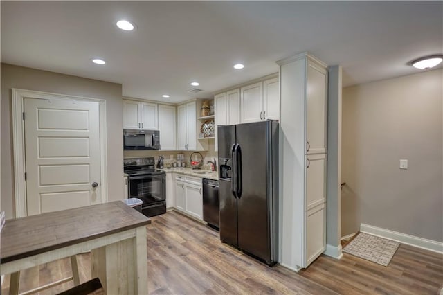 kitchen featuring open shelves, a sink, light wood finished floors, and black appliances
