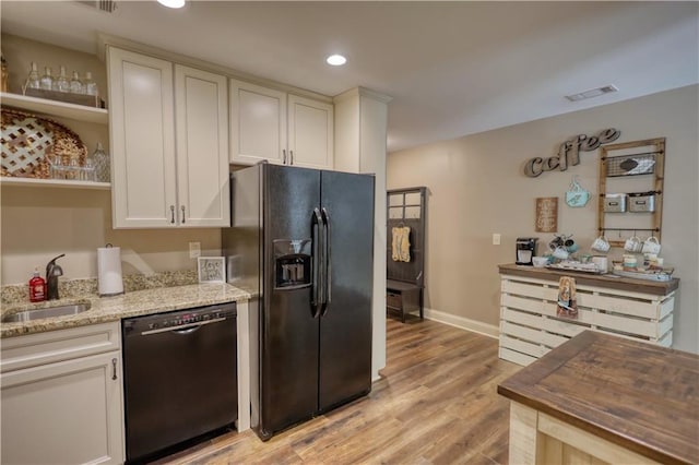 kitchen featuring open shelves, a sink, light wood-style flooring, visible vents, and black appliances