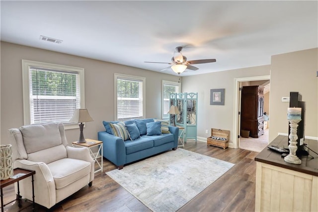 living area with baseboards, a ceiling fan, dark wood-style flooring, and visible vents