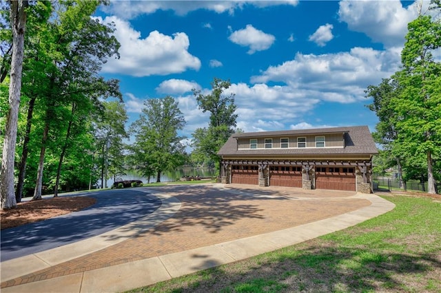 view of front of property with decorative driveway, fence, stone siding, and a garage