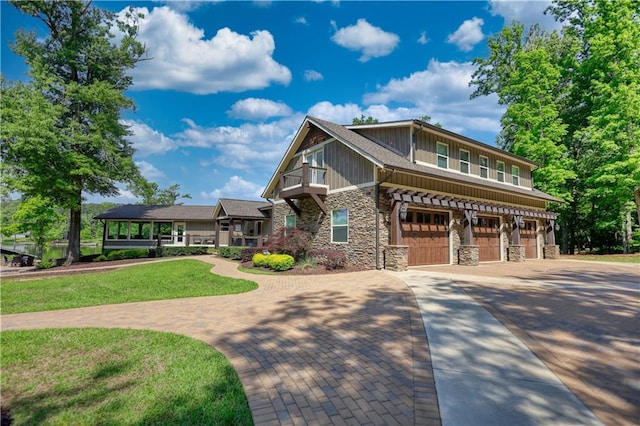 craftsman-style house with a garage, driveway, a front lawn, and stone siding
