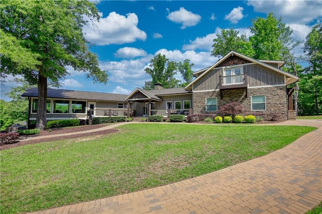 craftsman-style home with board and batten siding, a front lawn, and stone siding