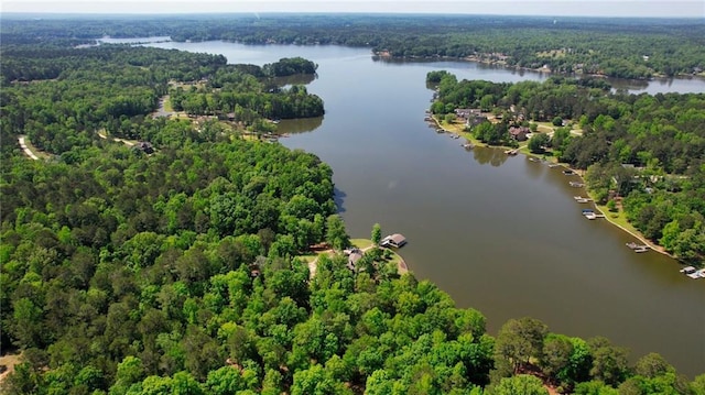 birds eye view of property featuring a water view and a wooded view