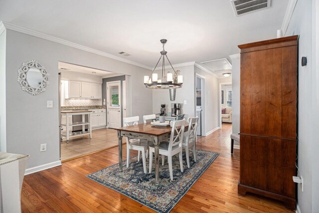 dining area with visible vents, ornamental molding, and light wood finished floors