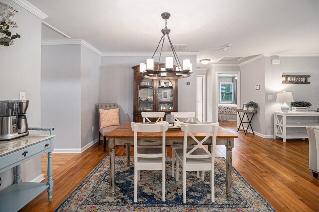 dining area with crown molding, baseboards, wood finished floors, and a notable chandelier
