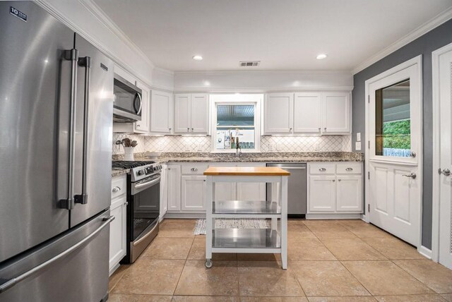 kitchen featuring decorative backsplash, white cabinets, and stainless steel appliances