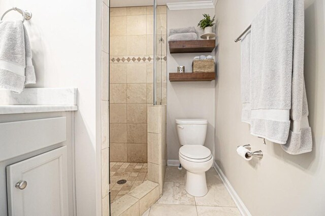 bathroom with crown molding, a tile shower, vanity, baseboards, and toilet