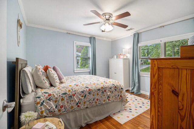 bedroom with visible vents, ornamental molding, wood finished floors, and multiple windows