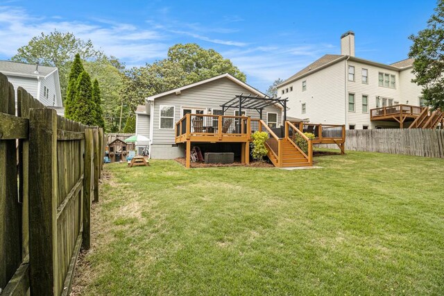 rear view of house with a lawn, a deck, a fenced backyard, and a pergola