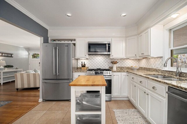 kitchen featuring crown molding, a sink, wood counters, stainless steel appliances, and white cabinetry