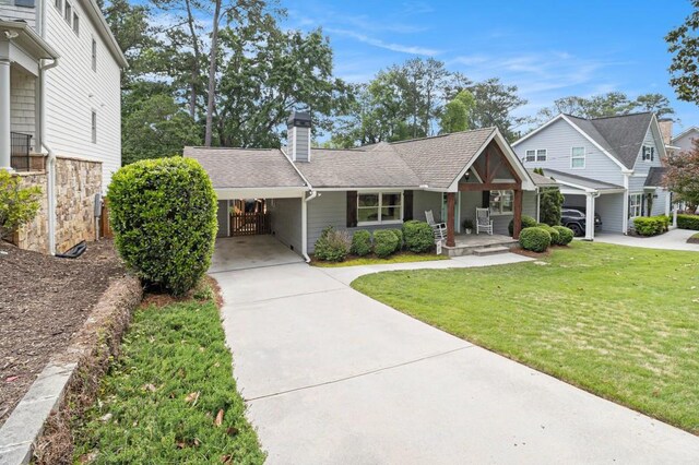 view of front of house with a porch, a chimney, a front lawn, concrete driveway, and an attached carport