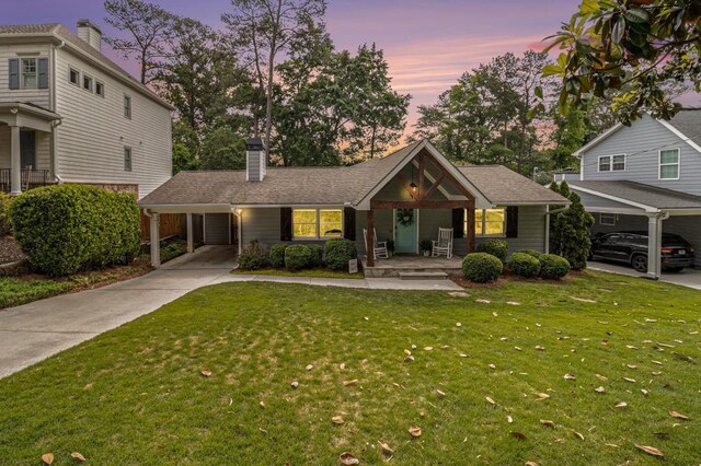 view of front of house featuring a front yard, a chimney, a porch, driveway, and a carport