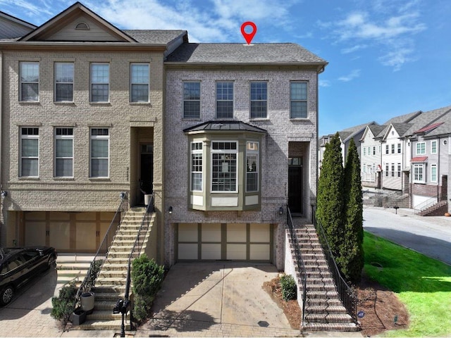 multi unit property featuring brick siding, stairway, an attached garage, and concrete driveway