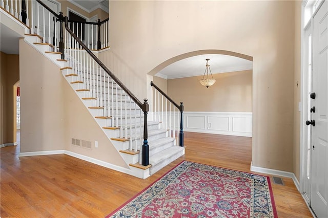 foyer entrance with hardwood / wood-style floors, ornamental molding, and a high ceiling