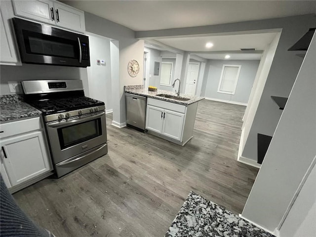 2040 Penelope St NW, Atlanta, GA 30314 - kitchen featuring appliances with stainless steel finishes, a sink, baseboards, light stone counters, and a peninsula