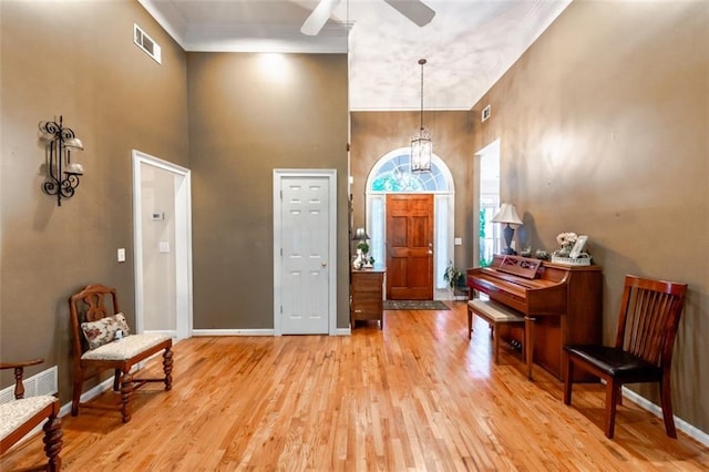 living area with a chandelier, light wood-type flooring, baseboard heating, and crown molding