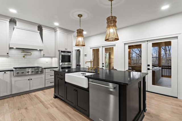 kitchen with french doors, sink, hanging light fixtures, custom range hood, and stainless steel appliances