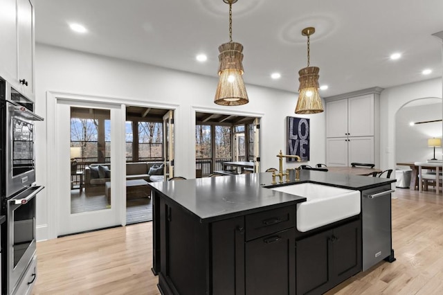 kitchen with sink, white cabinetry, hanging light fixtures, an island with sink, and stainless steel appliances