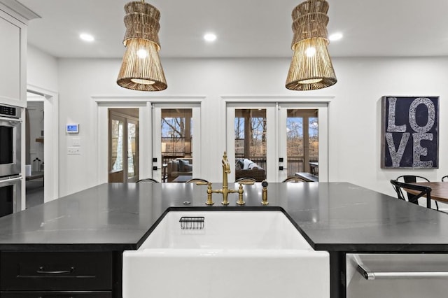 kitchen featuring french doors, white cabinetry, a center island, and sink