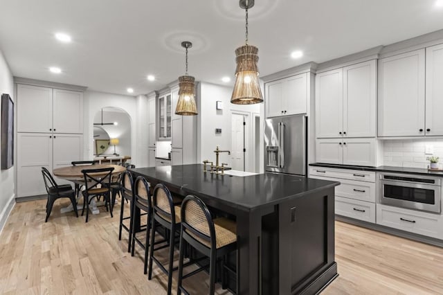 kitchen featuring decorative light fixtures, tasteful backsplash, sink, a kitchen island with sink, and stainless steel appliances