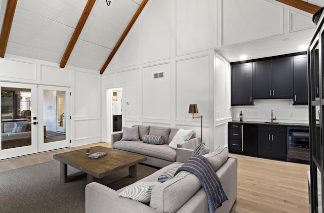 living room with light hardwood / wood-style floors, beam ceiling, high vaulted ceiling, and beverage cooler