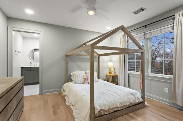 bedroom with sink, ensuite bathroom, ceiling fan, and light wood-type flooring