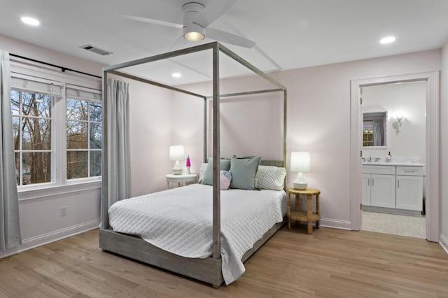 bedroom featuring light hardwood / wood-style floors, sink, ceiling fan, and ensuite bath