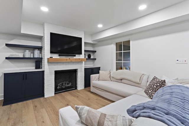 living room featuring a brick fireplace and light hardwood / wood-style floors