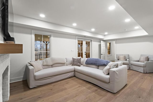 living room featuring french doors, a fireplace, and light wood-type flooring