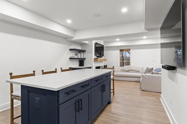 kitchen with blue cabinetry, a kitchen bar, a kitchen island, and light wood-type flooring