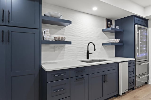 kitchen with wine cooler, blue cabinets, light hardwood / wood-style floors, and sink