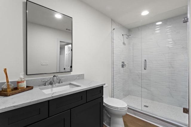 bathroom featuring vanity, an enclosed shower, wood-type flooring, and toilet