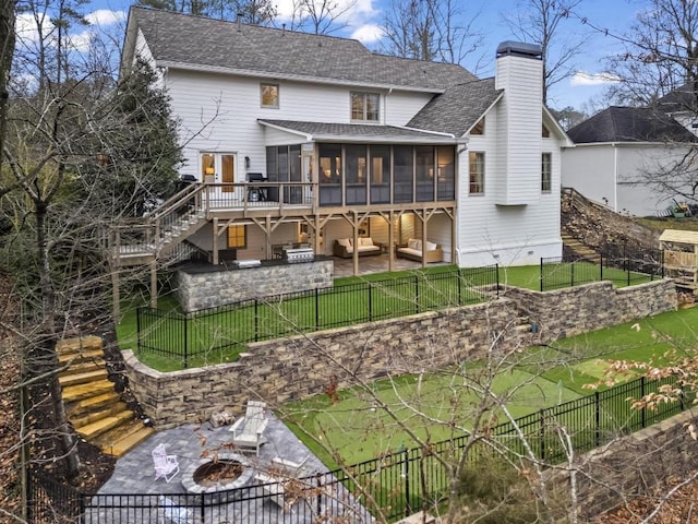 rear view of property with a patio, a lawn, an outdoor kitchen, an outdoor living space with a fire pit, and a sunroom