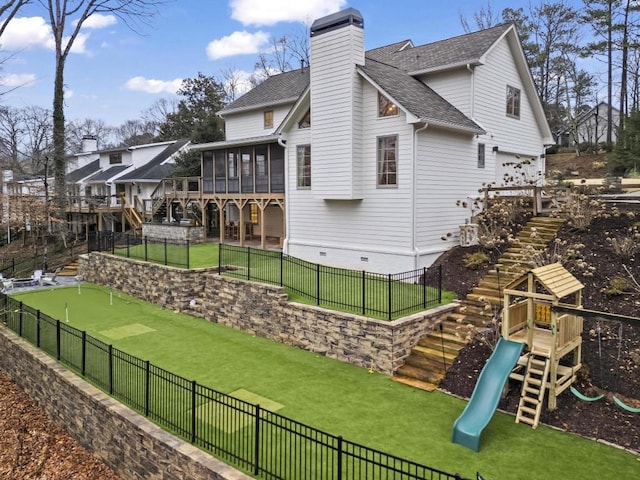 back of house with a playground, a sunroom, and a yard