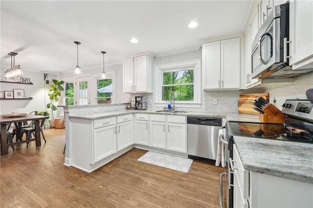 kitchen featuring a peninsula, white cabinetry, tasteful backsplash, a sink, and appliances with stainless steel finishes