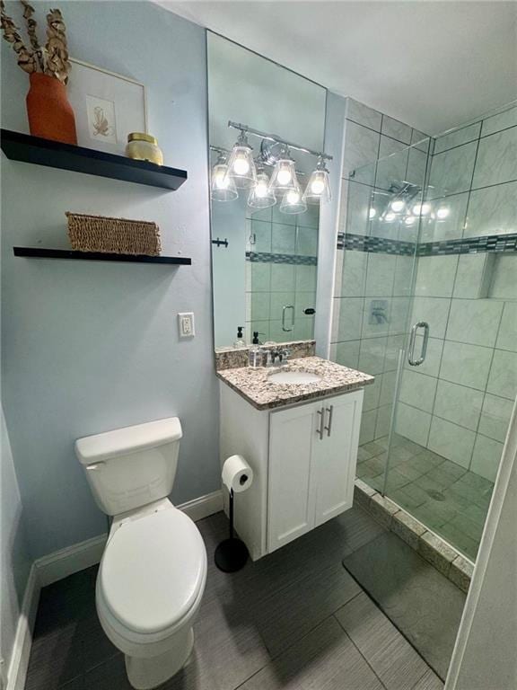 bathroom featuring tile patterned flooring, vanity, toilet, baseboards, and a shower stall