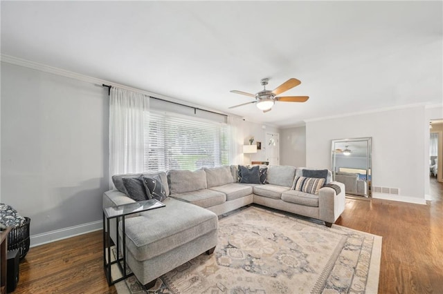living area with crown molding, a ceiling fan, visible vents, and wood finished floors