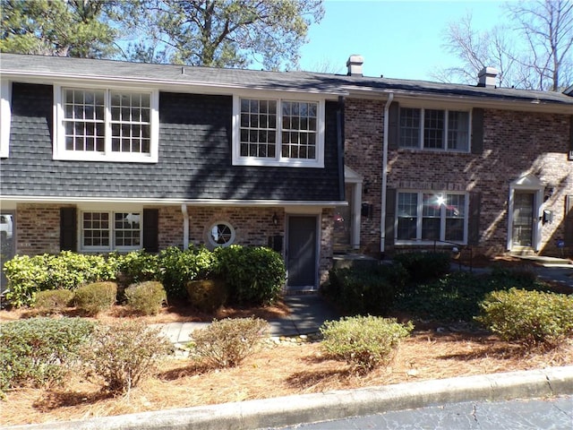 view of front of home with brick siding and a shingled roof