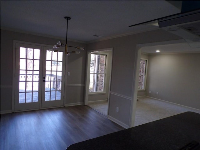 unfurnished dining area with baseboards, ornamental molding, wood finished floors, and french doors