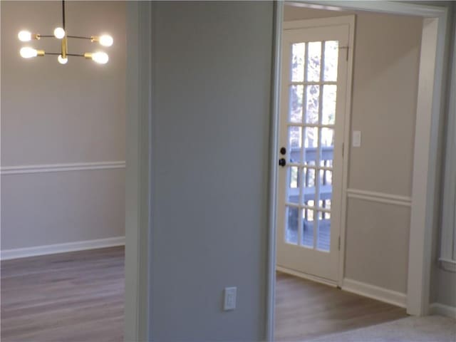 interior space featuring a notable chandelier, baseboards, and wood finished floors