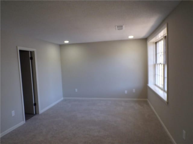 spare room with carpet, visible vents, and baseboards