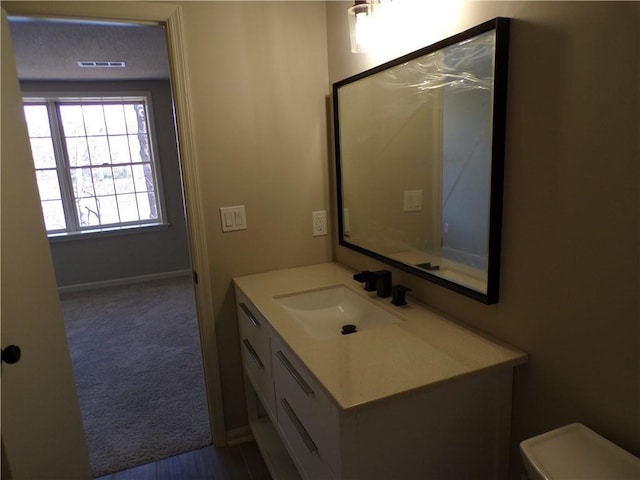 bathroom featuring baseboards, vanity, and toilet