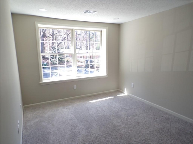 spare room with a textured ceiling, baseboards, visible vents, and a healthy amount of sunlight