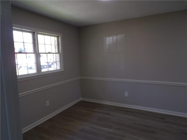 unfurnished room with baseboards and dark wood-style flooring