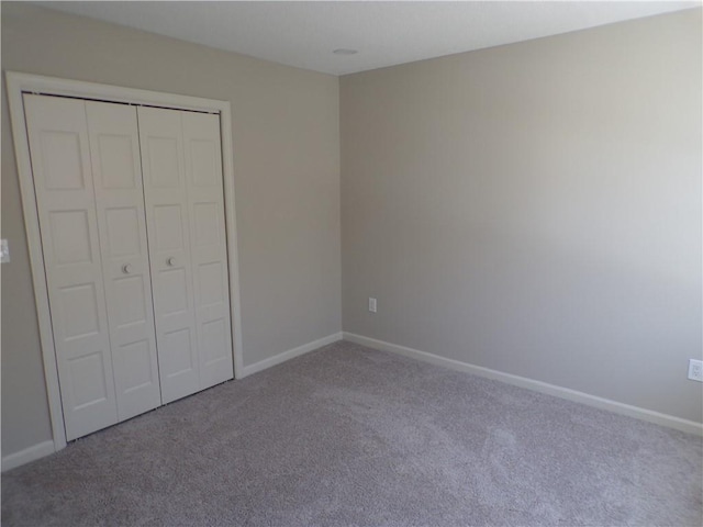 unfurnished bedroom featuring carpet, baseboards, and a closet