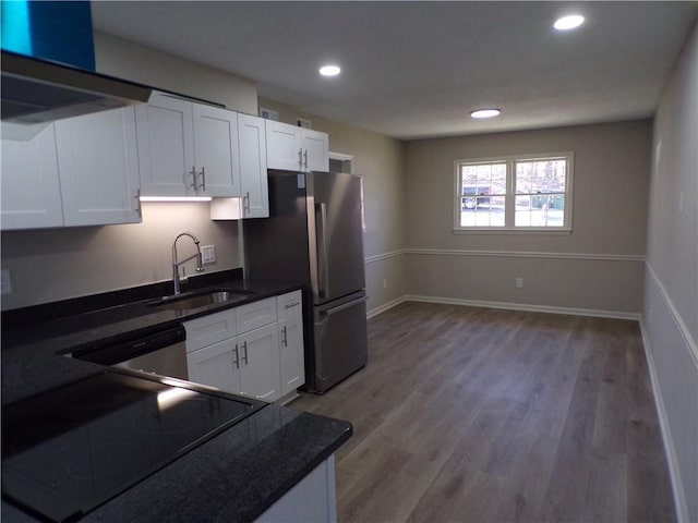 kitchen featuring light wood finished floors, baseboards, appliances with stainless steel finishes, white cabinetry, and a sink