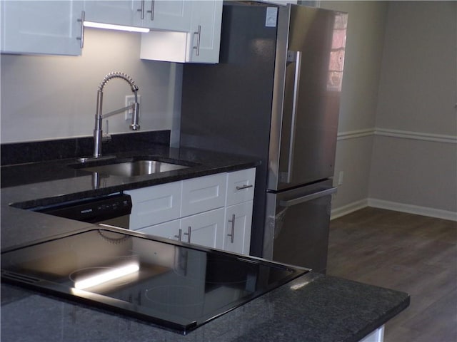 kitchen with white cabinetry, a sink, baseboards, and wood finished floors